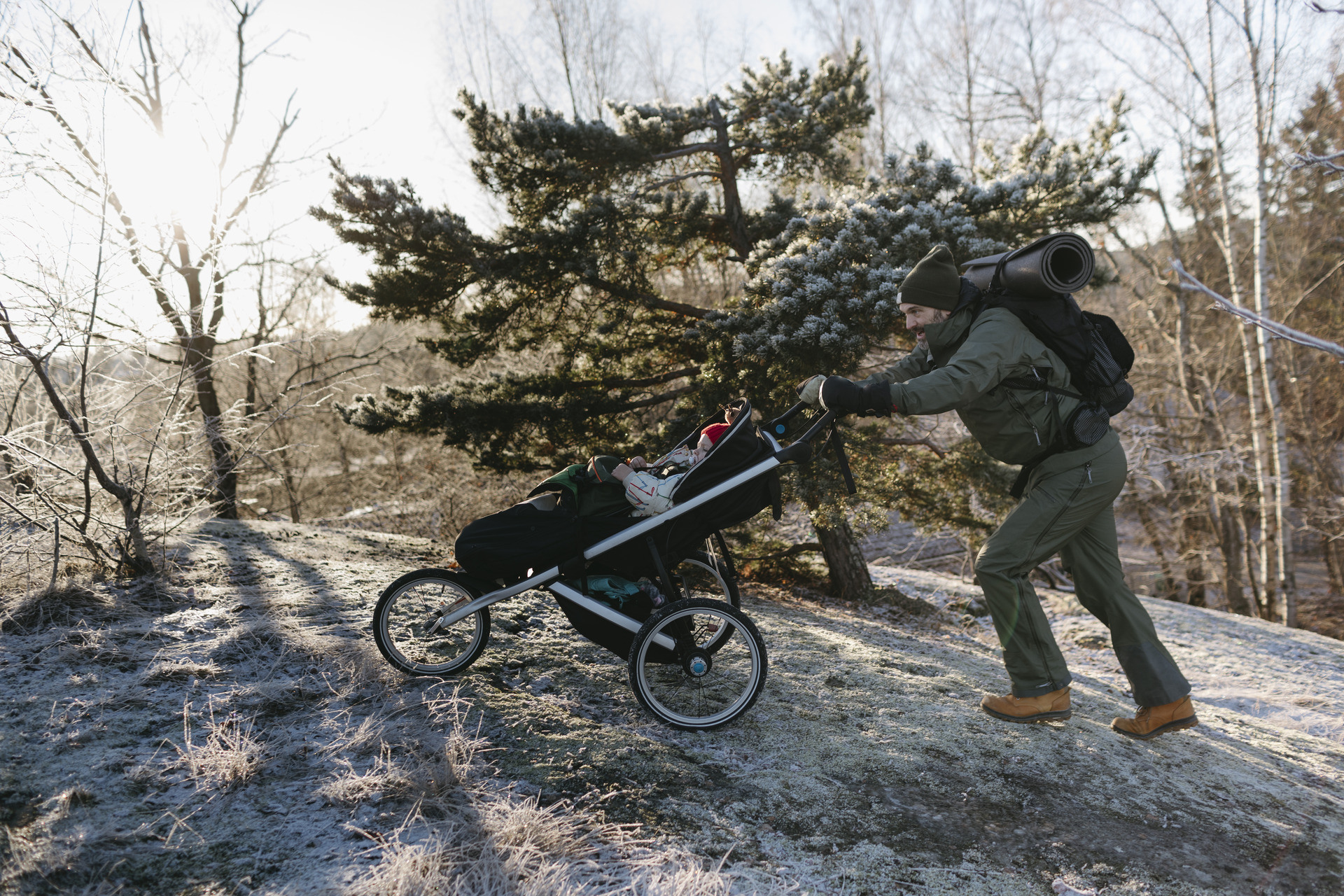 Mann i skogen dytter en barnevogn opp en bakke