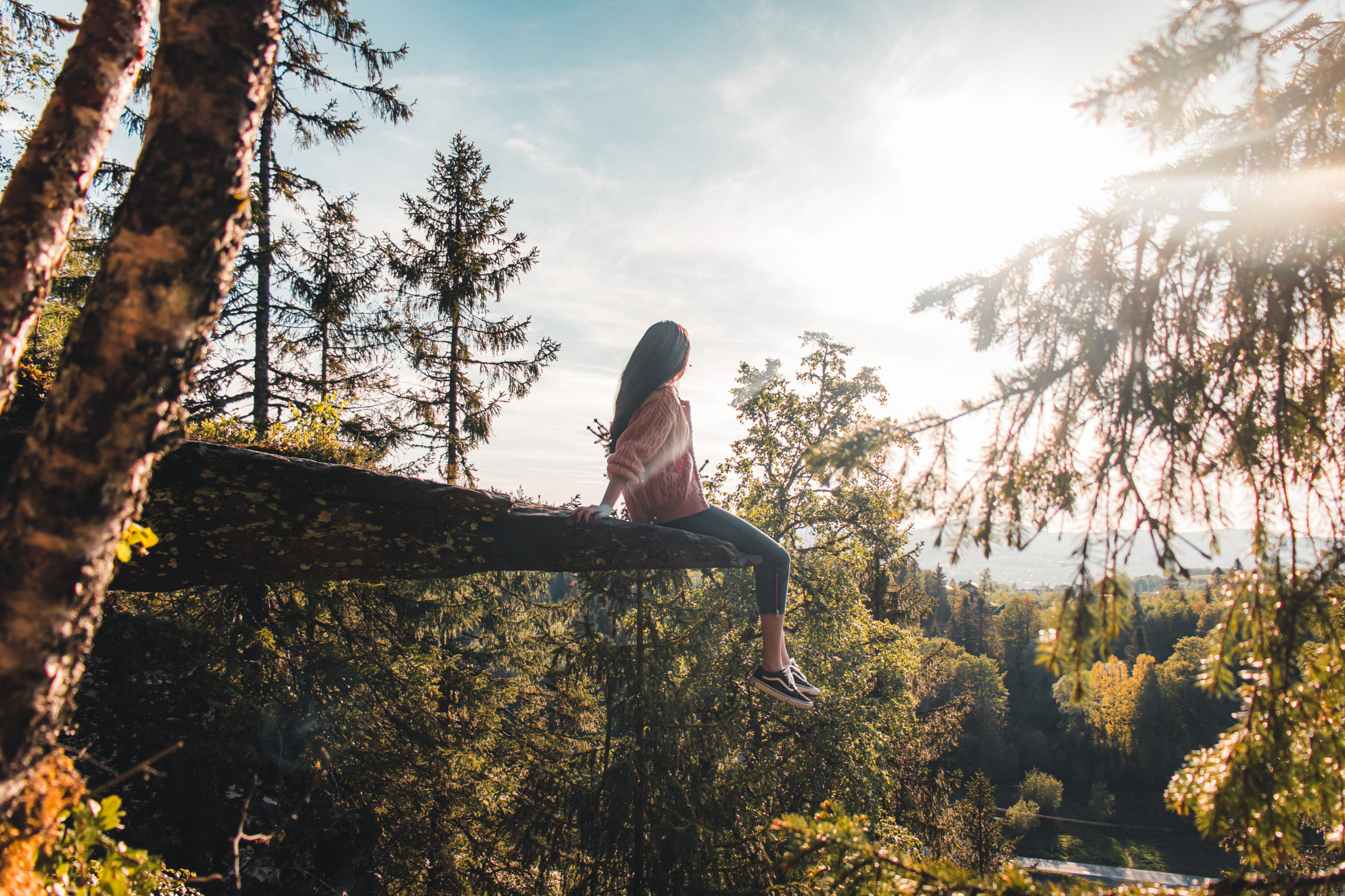 Kvinne sitter i vår vær og nyter utsikten på Burmaklippen i Trondheim