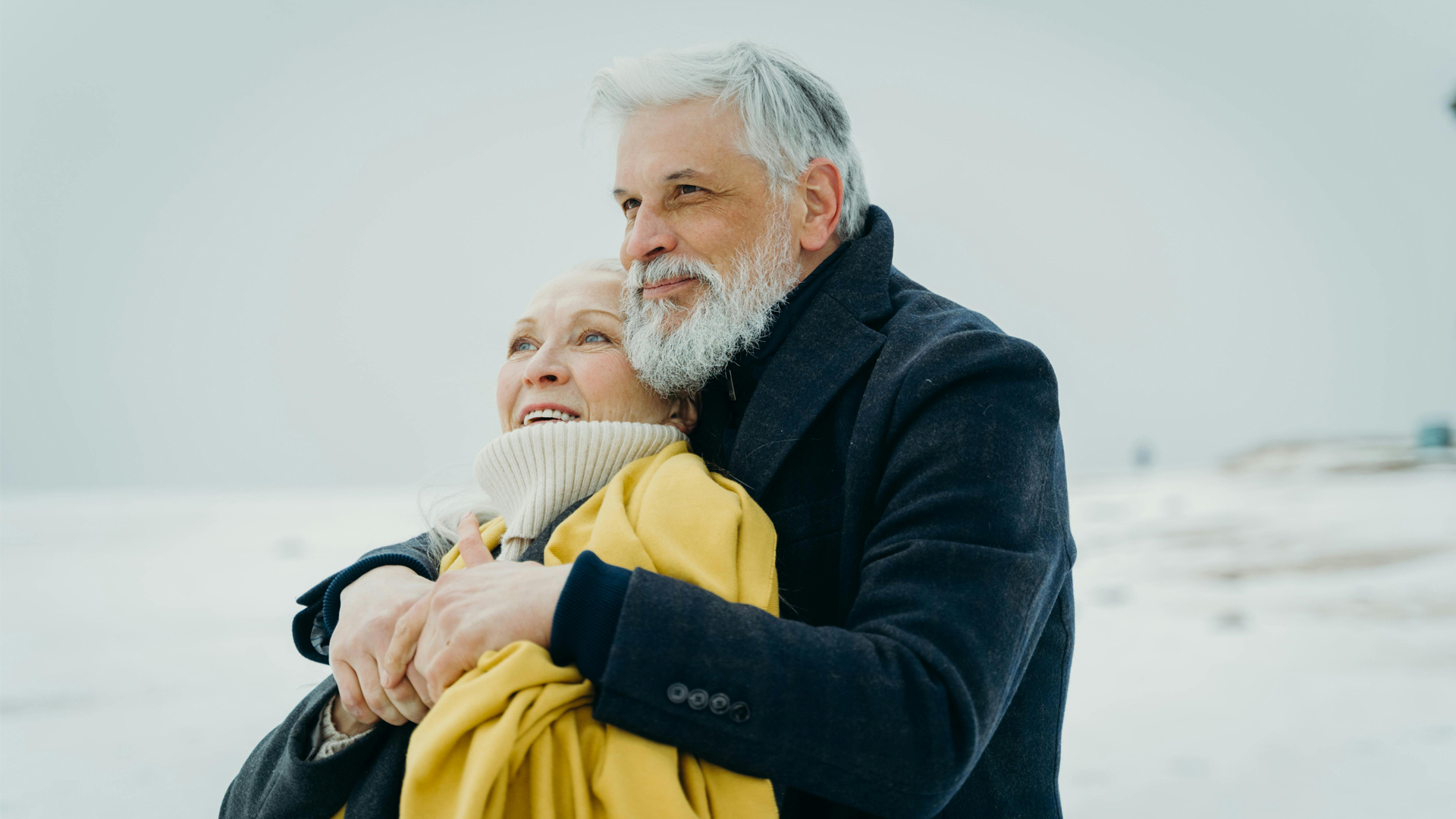 Mann og kvinne står sammen i høstvær på stranden