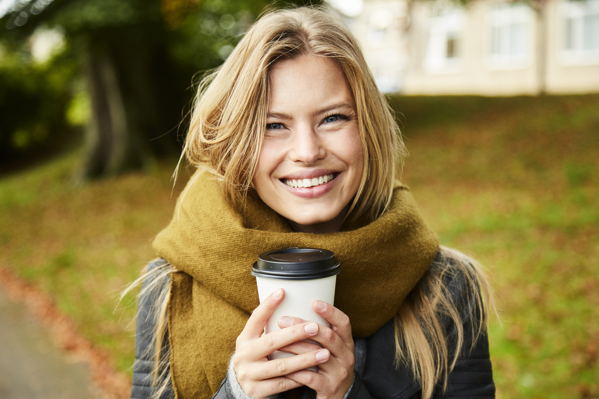 Kvinne med kaffe ser mot kamera